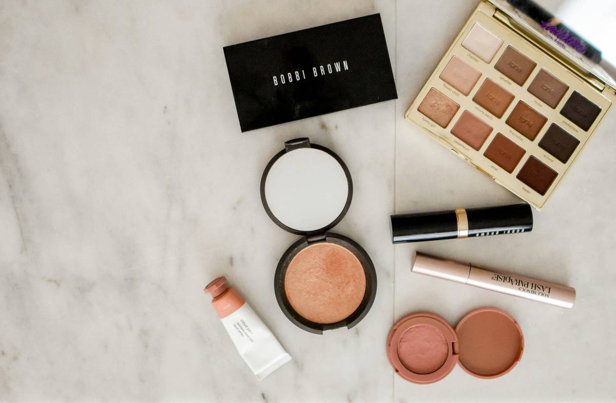 Elite Brands makeup collection featuring foundation, lipstick, and eyeshadow on velvet backdrop