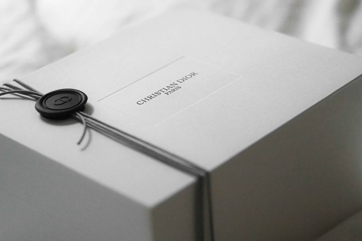 Designer Packaging featuring a gold-toned luxury compact with mirror and embossed logo on velvet surface